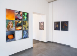 Eine moderne Kunstgalerie mit weißen Wänden, die verschiedene farbenfrohe Fotografien zeigt, darunter ein Raster aus neun Bildern an der linken Wand und zwei Paarbilder sowie ein Einzelbild an der rechten Wand. Der Boden ist mit grauen Fliesen ausgelegt. 